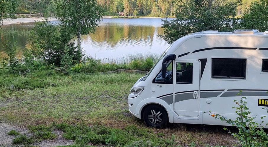 Får man fricampa med husbil på badplatsen? Husbil står på gräs vid sjö