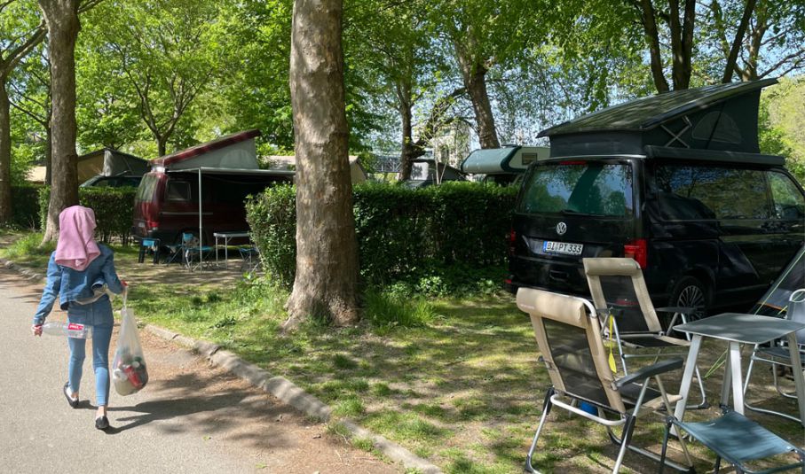 Plåtisarna med popup-tak står på rad på Camping de Paris. Flicka med håret i handduk går förbi plåtisar med popup-tak