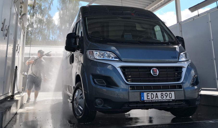 Att ta hand om husbilen är a och o om man vill att den ska få ett bra andrahandsvärde. Man i shorts sprutar vatten på husbil byggd på Fiat Ducato