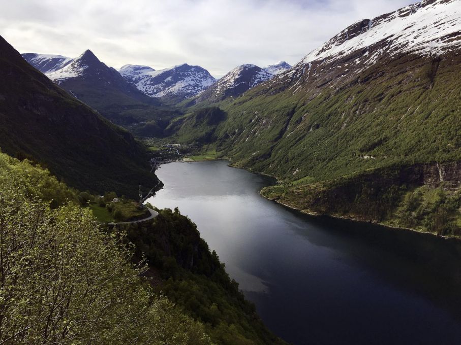 Geiranger med en av kurvorna ned mot byn. På motsatt sida syns de snöklädda topparna där vägen fortsätter åter upp på fjället. Är vädret bra rekommenderas turen upp på Dalsnibba (1500 möh) mitt i bilden. Därifrån är utsikten magnifik. Se bilder längre fram i detta bildspel.