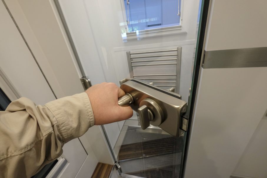 Duschen har glasdörr med gediget metallhandtag.